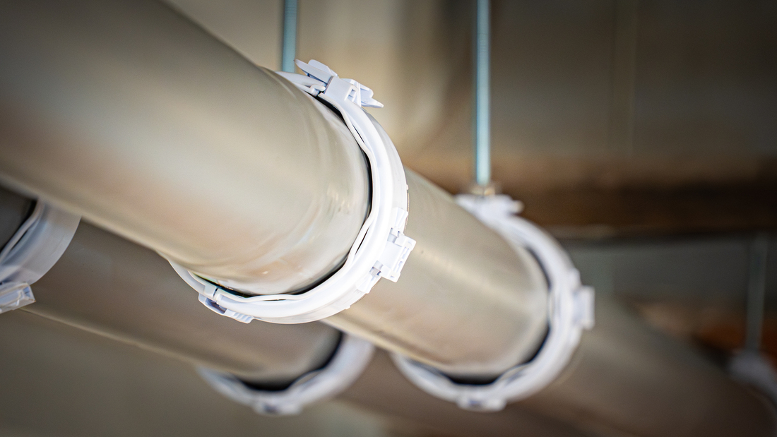 Close-up view of suspended innoflue secured with white octoclamps in an indoor installation.